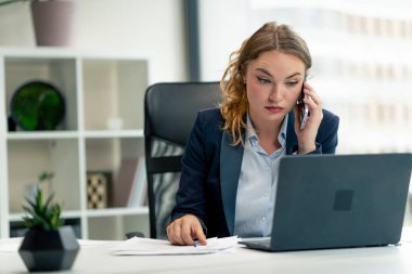 Modern bir ofiste geniş pencereli mavi gömlekli güzel bir işçi ve dizüstü bilgisayarlı genç bir patron.