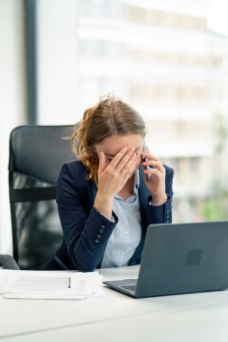 Modern bir ofiste geniş pencereli mavi gömlekli güzel bir işçi ve dizüstü bilgisayarlı genç bir patron.