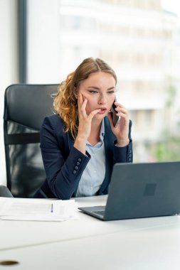 Modern bir ofiste geniş pencereli mavi gömlekli güzel bir işçi ve dizüstü bilgisayarlı genç bir patron.