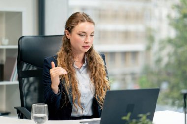 in a modern office with a large window a beautiful worker in a blue shirt with a laptop talk on a video call establishing friendship between companies clipart