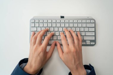 Modern bir ofiste, mavi tişörtlü, masa başında klavyeye yazı yazan güzel bir kadın.