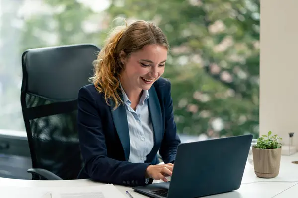Geniş pencereli modern bir ofiste mavi gömlekli güzel bir işçi kameraya bakar genç bir patron.