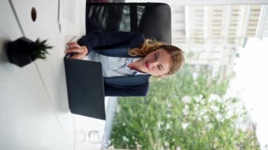 Modern bir ofiste, geniş pencereli bir dikey video dizüstü bilgisayarlı güzel bir işçi kameraya bakar genç bir patron.