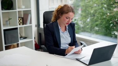 Modern bir ofiste geniş pencereli mavi gömlekli güzel bir işçi laptoplu genç bir patron belgelerle çalışıyor.
