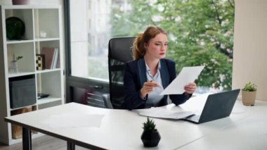 Modern bir ofiste geniş pencereli mavi gömlekli güzel bir işçi laptoplu genç bir patron belgelerle çalışıyor.