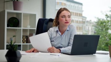 Modern bir ofiste geniş pencereli mavi gömlekli güzel bir işçi laptoplu genç bir patron belgelerle çalışıyor.