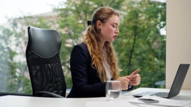 Modern bir ofiste geniş bir penceresi olan mavi gömlekli güzel bir işçi dizüstü bilgisayarlı bir konuşma yaparak şirketler arasında arkadaşlık kuran bir video görüşmesi yaptı.