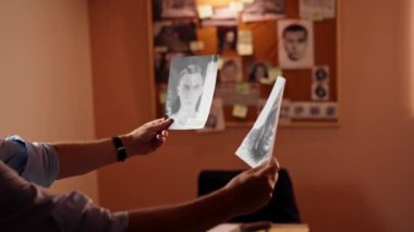 Dedektiflik bürosunda, gömlekli ve kravatlı orta yaşlı bir dedektif büyüteçle inceler kanıt inceler suçlu fotofit güzergahı suçlularını bulmak için ipuçlarını inceler.