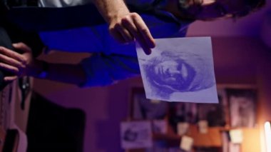 Dikey video, dedektiflik bürosunu kapatın. Gömlekli ve kravatlı orta yaşlı bir müfettiş büyüteçle inceler. Kanıt, suçlunun fotofit rotasını araştıran ipuçlarını inceler.