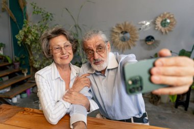 Usta sınıf yaşlılar için mutlu yaşlı bir çift modern bir şekilde telefonda fotoğraf çekiyor hoş anılar.