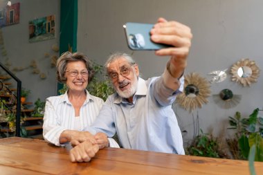 Usta sınıf yaşlılar için mutlu yaşlı bir çift modern bir şekilde telefonda fotoğraf çekiyor hoş anılar.