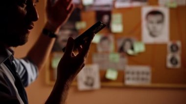 Yakın plan dedektiflik bürosu gömlekli ve kravatlı araştırmacı. Telefonda konuşarak gerçeği bulmak için ipucu panosunun yanında duruyor.