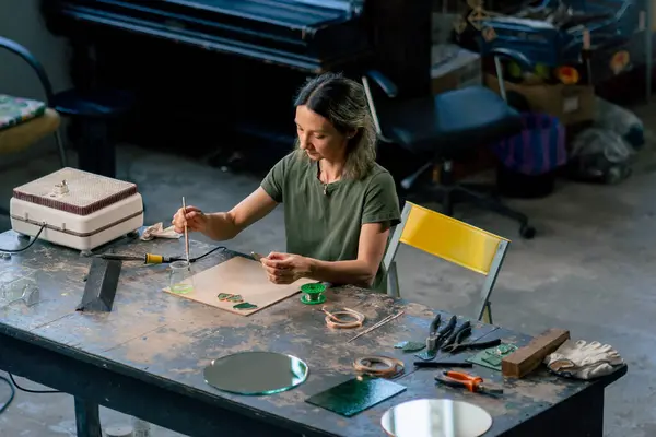 stock image in a large green workshop on a woman with green hair creates decorative flowers working with metal tape decor on the mirror handicrafts