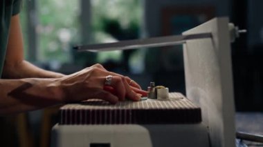 Büyük yeşil bir atölyeye yakın bir yerde öğütme makinesinin ahşap masasında yeşil saçlı zayıf bir kadın cam bir ürünün ucunu damak zevkine getiriyor, köşeleri parlatıyor, el yapımı.