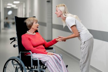 Modern bir klinikte, beyaz bir koridorda, bebek arabasındaki yaşlı bir kadın torununu elinden tutar ve her şeyin yoluna gireceğini söyler, onu sakinleştirir.