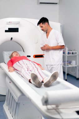 Modern bir klinikte, beyaz bir ofiste yaşlı bir kadının, yakınlardaki genç bir doktorun beyin MR 'ı için bir ilaç.