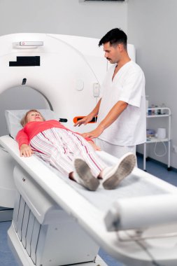 Modern bir klinikte, beyaz bir ofiste yaşlı bir kadının, yakınlardaki genç bir doktorun beyin MR 'ı için bir ilaç.