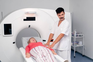 Modern bir klinikte, beyaz bir ofiste yaşlı bir kadının, yakınlardaki genç bir doktorun beyin MR 'ı için bir ilaç.