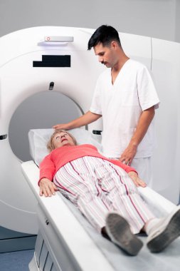 Modern bir klinikte, beyaz bir ofiste yaşlı bir kadının, yakınlardaki genç bir doktorun beyin MR 'ı için bir ilaç.