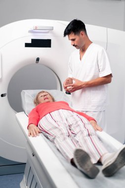 Modern bir klinikte, beyaz bir ofiste yaşlı bir kadının, yakınlardaki genç bir doktorun beyin MR 'ı için bir ilaç.