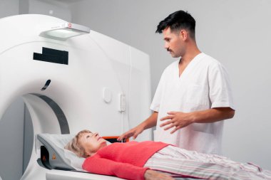 Modern bir klinikte, beyaz bir ofiste yaşlı bir kadının, yakınlardaki genç bir doktorun beyin MR 'ı için bir ilaç.