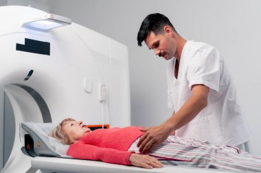 Modern bir klinikte, beyaz bir ofiste yaşlı bir kadının, yakınlardaki genç bir doktorun beyin MR 'ı için bir ilaç.