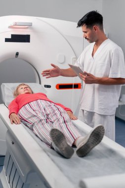 Modern bir klinikte, beyaz bir ofiste yaşlı bir kadının, yakınlardaki genç bir doktorun beyin MR 'ı için bir ilaç.