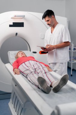 Modern bir klinikte, beyaz bir ofiste yaşlı bir kadının, yakınlardaki genç bir doktorun beyin MR 'ı için bir ilaç.