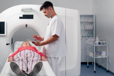 Modern bir klinikte, beyaz bir ofiste yaşlı bir kadının, yakınlardaki genç bir doktorun beyin MR 'ı için bir ilaç.