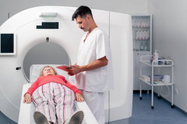 Modern bir klinikte, beyaz bir ofiste yaşlı bir kadının, yakınlardaki genç bir doktorun beyin MR 'ı için bir ilaç.