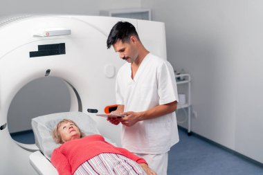 Modern bir klinikte, beyaz bir ofiste yaşlı bir kadının, yakınlardaki genç bir doktorun beyin MR 'ı için bir ilaç.