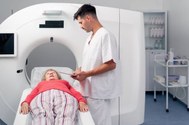 Modern bir klinikte, beyaz bir ofiste yaşlı bir kadının, yakınlardaki genç bir doktorun beyin MR 'ı için bir ilaç.