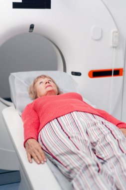 Beyaz bir ofisteki modern bir klinikte yaşlı bir kadının, yakınlardaki genç bir doktorun beyin MR 'ı için bir ilaç.