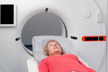 Beyaz bir ofisteki modern bir klinikte yaşlı bir kadının, yakınlardaki genç bir doktorun beyin MR 'ı için bir ilaç.