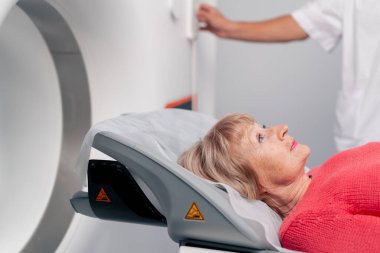 Beyaz bir ofisteki modern bir klinikte yaşlı bir kadının, yakınlardaki genç bir doktorun beyin MR 'ı için bir ilaç.