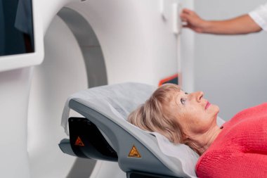 Beyaz bir ofisteki modern bir klinikte yaşlı bir kadının, yakınlardaki genç bir doktorun beyin MR 'ı için bir ilaç.