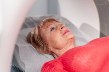 Beyaz bir ofisteki modern bir klinikte yaşlı bir kadının, yakınlardaki genç bir doktorun beyin MR 'ı için bir ilaç.