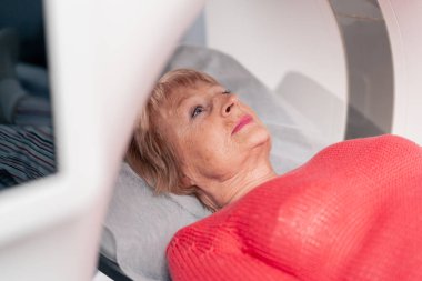 Beyaz bir ofisteki modern bir klinikte yaşlı bir kadının, yakınlardaki genç bir doktorun beyin MR 'ı için bir ilaç.