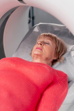 Beyaz bir ofisteki modern bir klinikte yaşlı bir kadının, yakınlardaki genç bir doktorun beyin MR 'ı için bir ilaç.