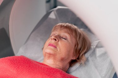 Beyaz bir ofisteki modern bir klinikte yaşlı bir kadının, yakınlardaki genç bir doktorun beyin MR 'ı için bir ilaç.