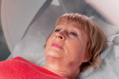 Beyaz bir ofisteki modern bir klinikte yaşlı bir kadının, yakınlardaki genç bir doktorun beyin MR 'ı için bir ilaç.