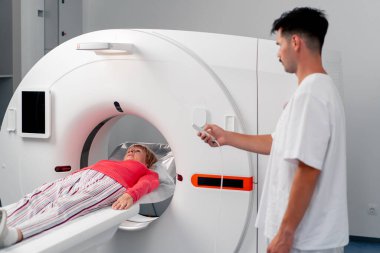 Modern bir klinikte, beyaz bir ofiste yaşlı bir kadının, yakınlardaki genç bir doktorun beyin MR 'ı için bir ilaç.