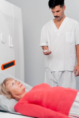 Modern bir klinikte, beyaz bir ofiste yaşlı bir kadının, yakınlardaki genç bir doktorun beyin MR 'ı için bir ilaç.