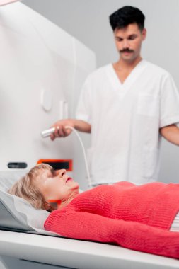 Modern bir klinikte, beyaz bir ofiste yaşlı bir kadının, yakınlardaki genç bir doktorun beyin MR 'ı için bir ilaç.