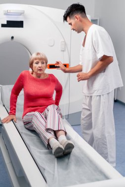 Modern bir klinikte, beyaz bir ofiste yaşlı bir kadının, yakınlardaki genç bir doktorun beyin MR 'ı için bir ilaç.