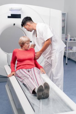 Modern bir klinikte, beyaz bir ofiste yaşlı bir kadının, yakınlardaki genç bir doktorun beyin MR 'ı için bir ilaç.