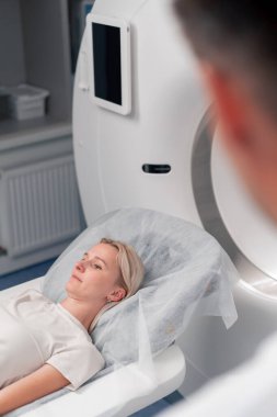 Modern bir klinikte, beyaz bir ofiste, MRI için bir ilaç, genç bir kızın beyninin incelenmesi, yıllık muayene
