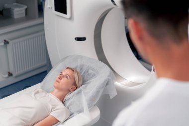 Modern bir klinikte, beyaz bir ofiste, MRI için bir ilaç, genç bir kızın beyninin incelenmesi, yıllık muayene