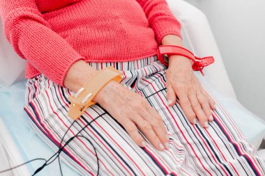 Modern bir klinikte, beyaz bir ofiste, kalp ritmini ölçen bir ilaç, kardiyogram, yaşlı bir kadın hastaya teşhis koyan bir doktor