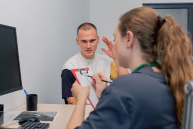 Modern bir klinikte, küçük bir terapistin ofisinde, steteskoplu genç bir kız doktor, genç bir adamla randevusunu gerçekleştirir.